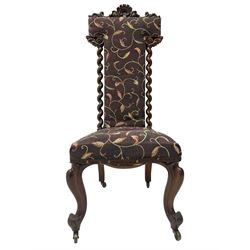 Victorian walnut prie-dieu chair, cresting rail carved with cartouche and extending scrolling foliage, back flanked by spiral turned column uprights, upholstered in foliate patterned fabric, raised on cabriole supports with scroll feet and castors