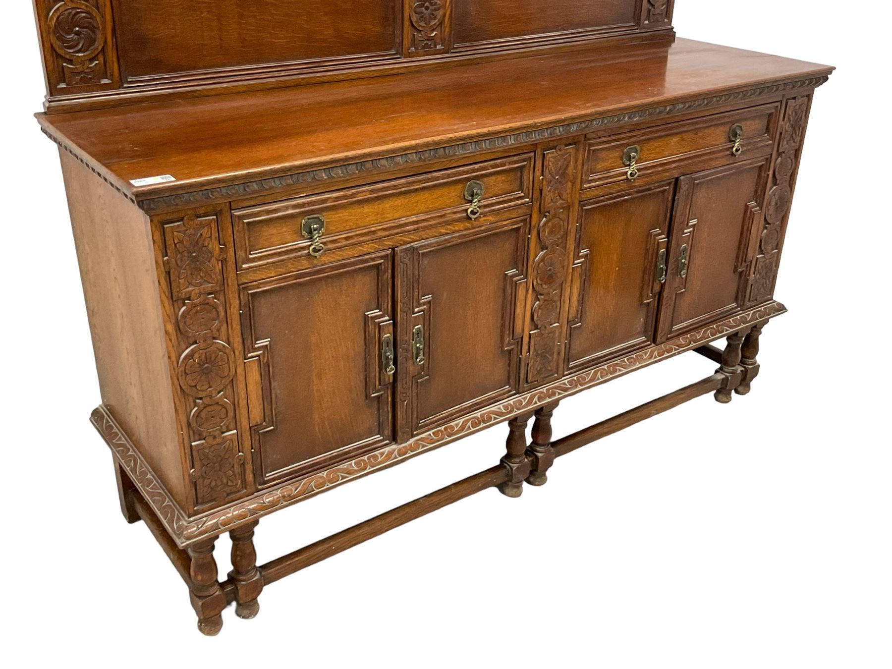 Early 20th century oak sideboard, raised panelled back with foliate carved decoration, rectangular top with gadrooned edge, fitted with two drawers over cupboards with field moulded facias, turned supports joined by stretchers