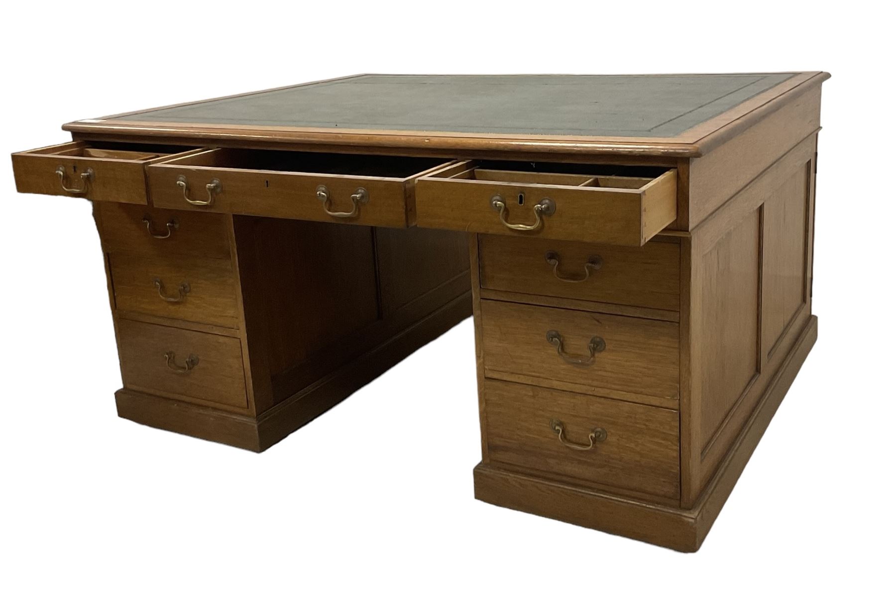 Late 19th century twin pedestal oak partner's desk, rectangular top with inset green leather writing surface, fitted with nine graduating drawers to each side, the rear drawers enclosed by panelled cupboards