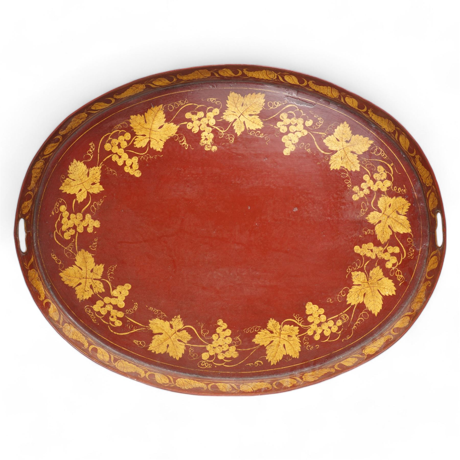 19th century red and parcel gilt toleware tray, of oval form with pierced handles, decorated with bands of fruiting vines and shells, L72cm x W55.5cm