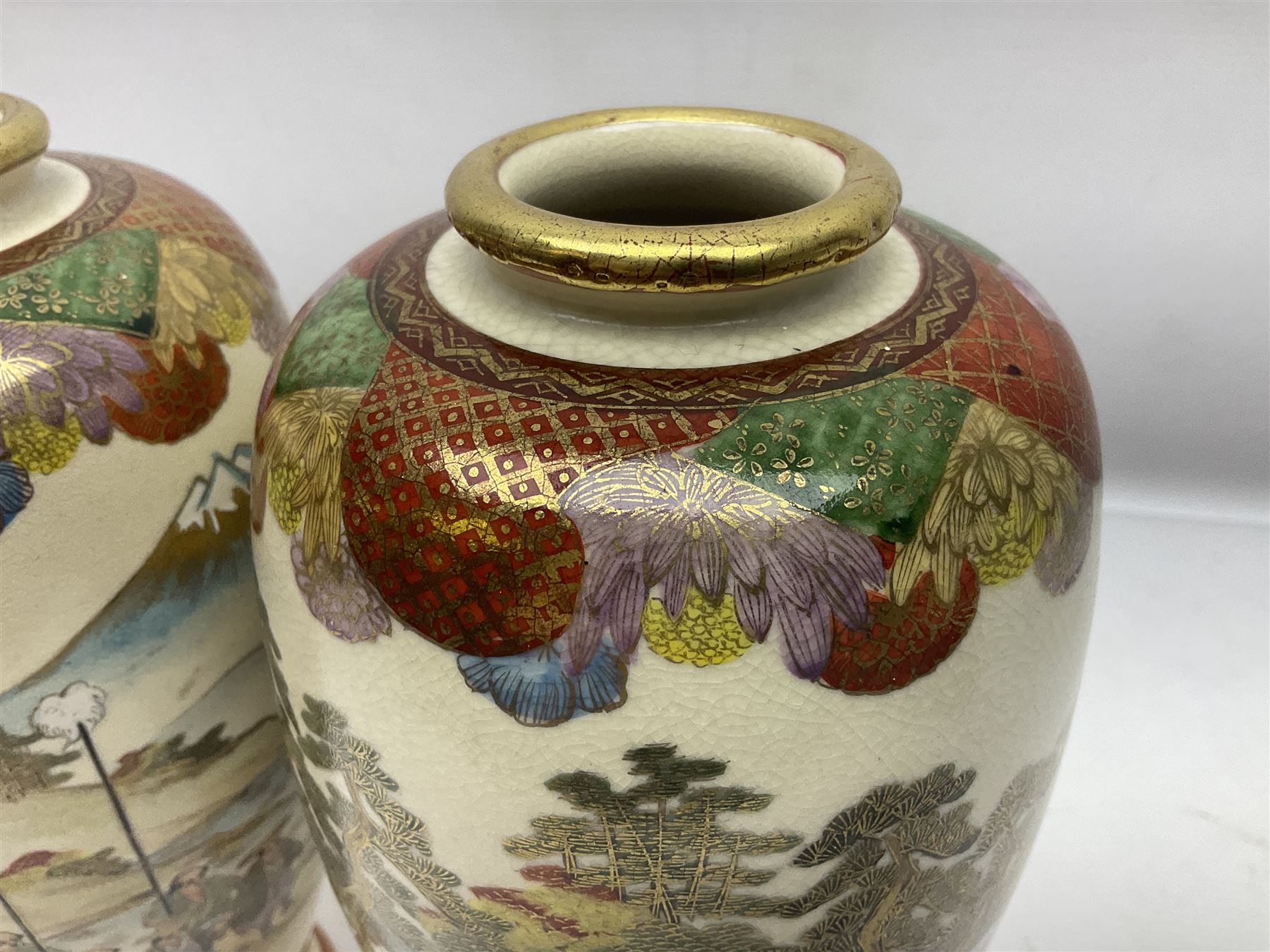 Pair of Japanese Meiji period Satsuma vases, decorated with scenes of procession within a mountainscape, with signature beneath, H25cm