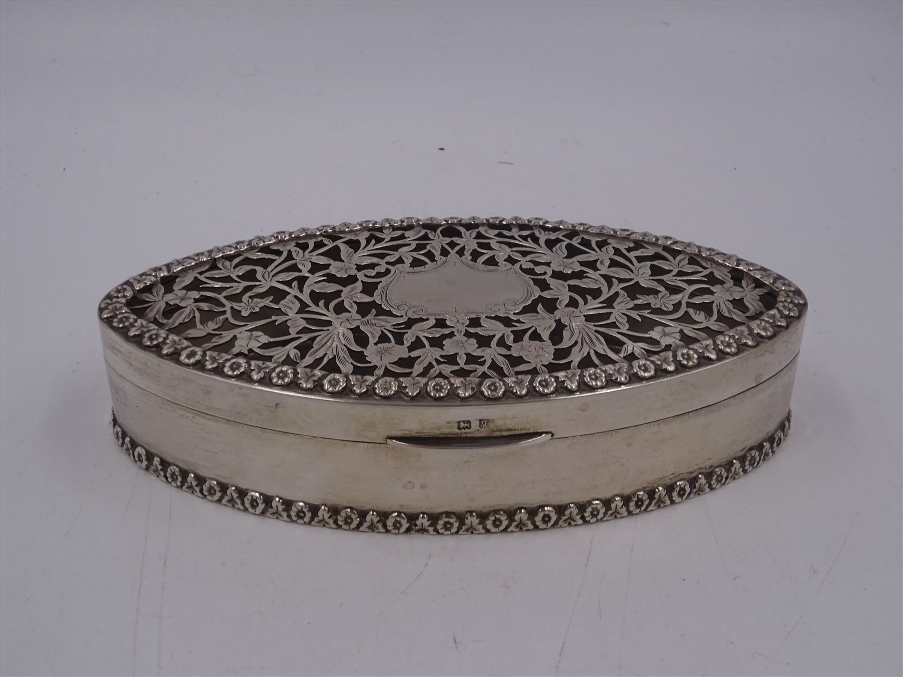 Edwardian silver trinket box, of navette form, the hinged cover with pierced floral and foliate decoration, and blank cartouche, hallmarked George Nathan & Ridley Hayes, Birmingham 1915 and stamped to base Pearce & Sons Silversmiths Leeds & York, W15.5cm, H3.5cm, 