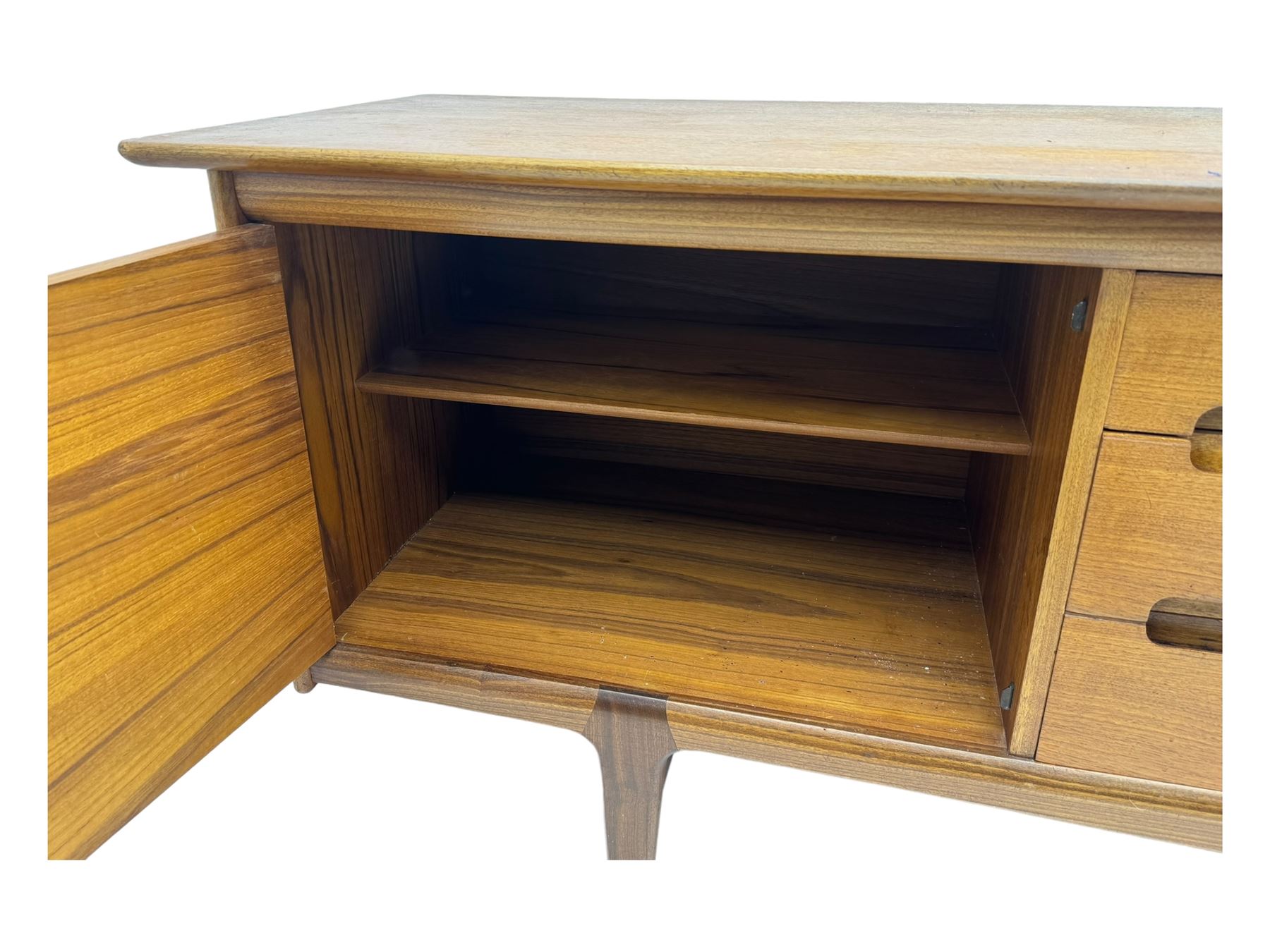 Younger - mid-20th century teak sideboard, rectangular top over three central drawers with recessed handles, flanked by two cupboard doors enclosing two shelves, on tapered supports joined by stretchers