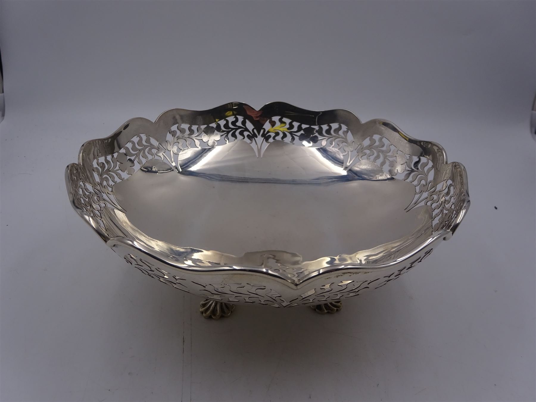 1920s silver bowl, of circular form with shaped rim, the sides with pierced foliate and floral decoration, upon four splayed feet, hallmarked Reid & Sons, London 1927, H9cm, D23cm