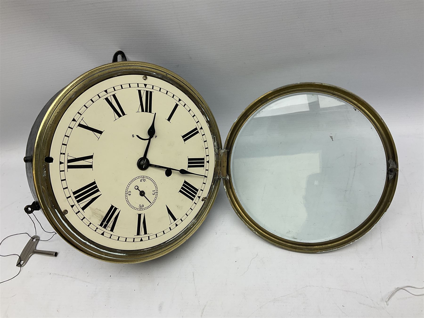 Seth Thomas ship's bulkhead clock with brass bezel and japanned case, the white dial with Roman numerals and subsidiary seconds dial D23.5cm; with key