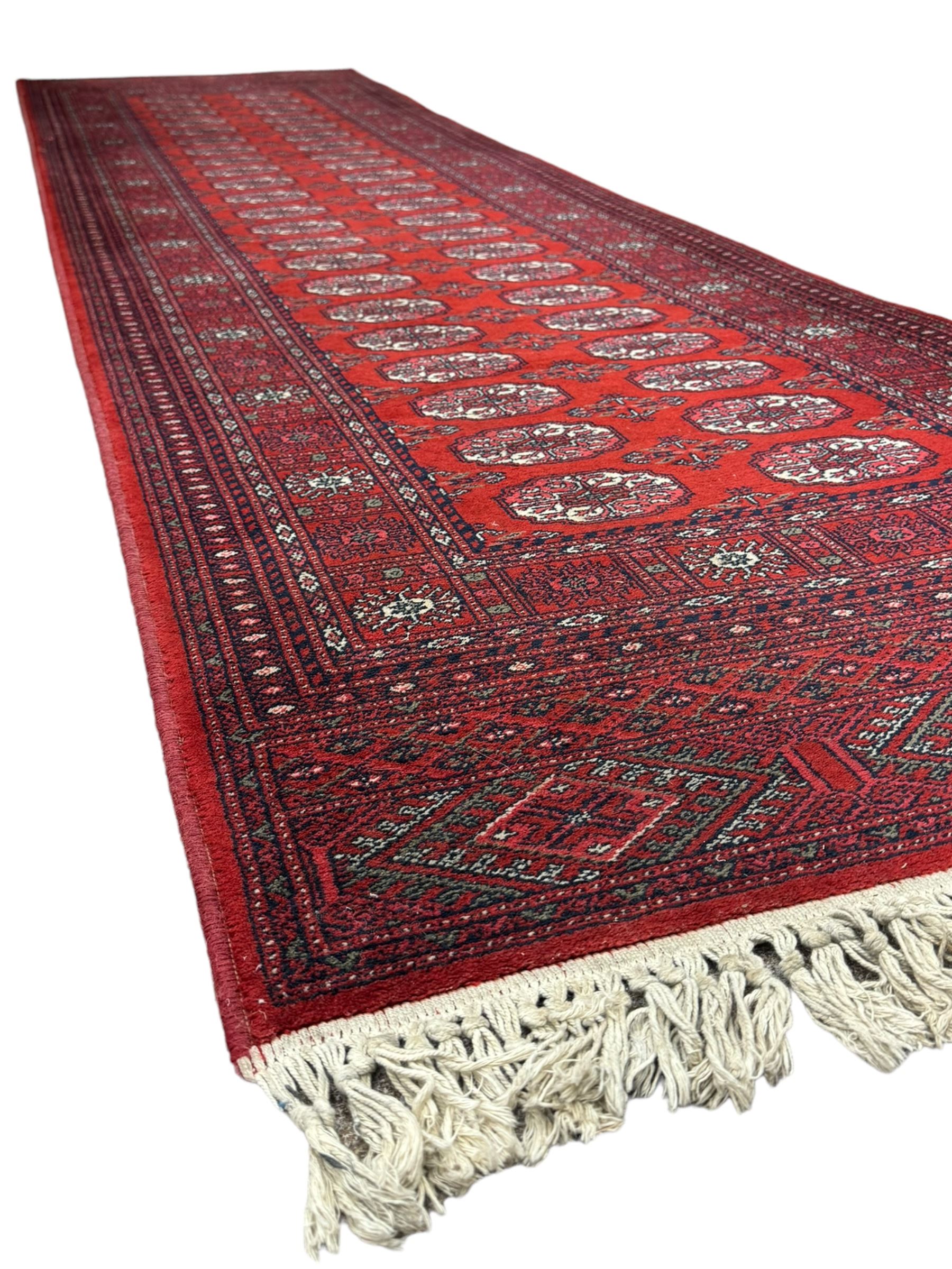 Persian Bokhara crimson ground runner rug, the field with a series of repeating ivory octagonal medallions, main border with repeating flower head pattern and diamonds within multiple guard stripes