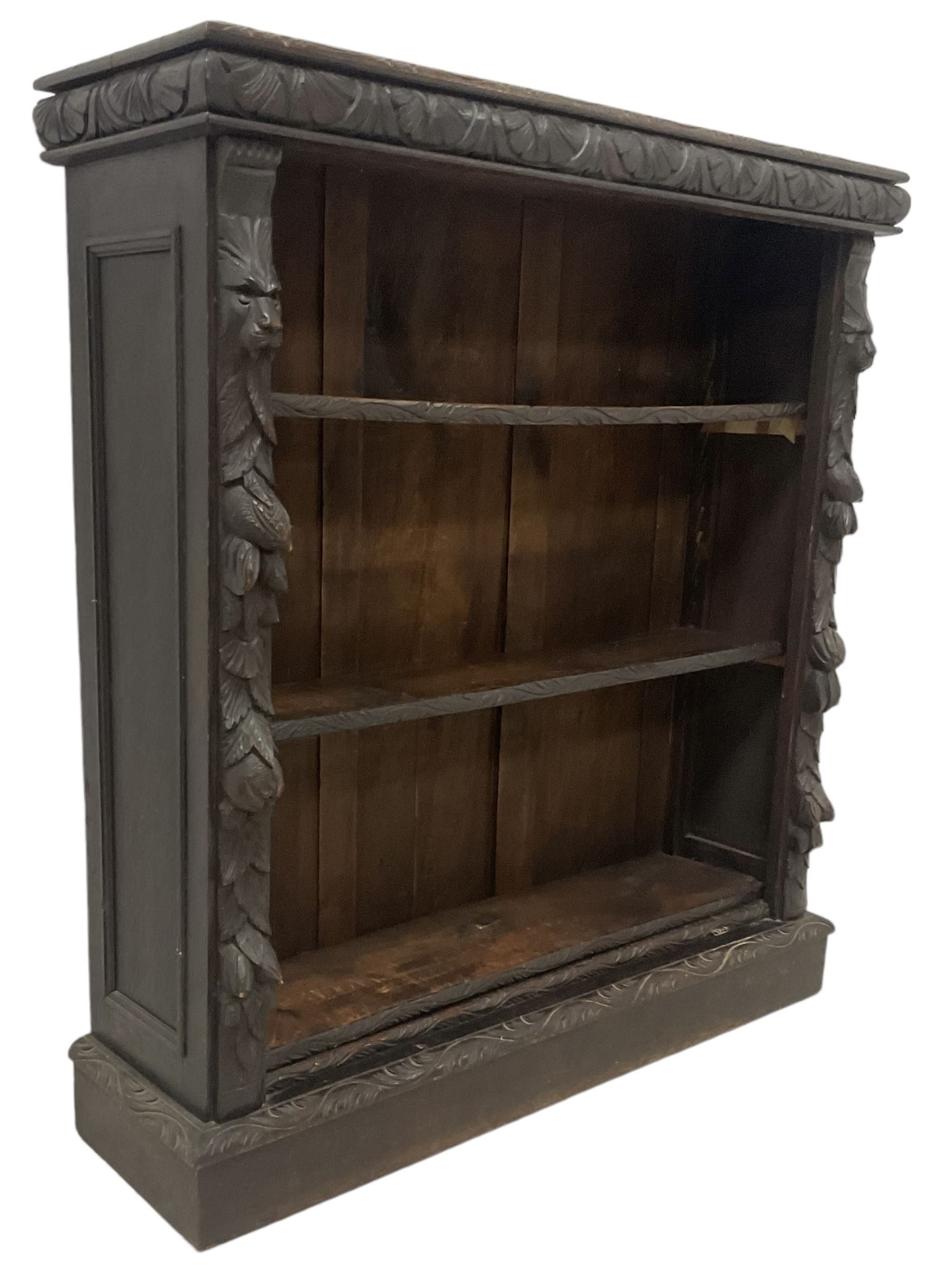 Victorian Jacobean revival carved oak open bookcase, cushion frieze carved with foliate decoration the pilasters decorated with applied carved lion masks and fruit motifs with extending leafage, two shelves over skirted base