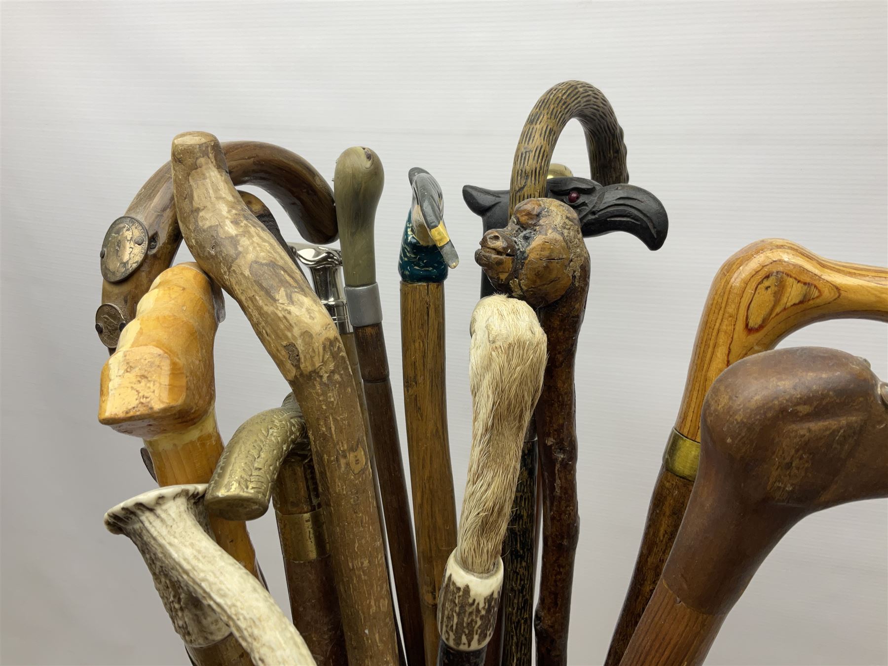 Oak barley twist stick stand, with a collection of walking sticks including examples with carved pommels, horn handles, silver collar etc, together with brass stick stand 