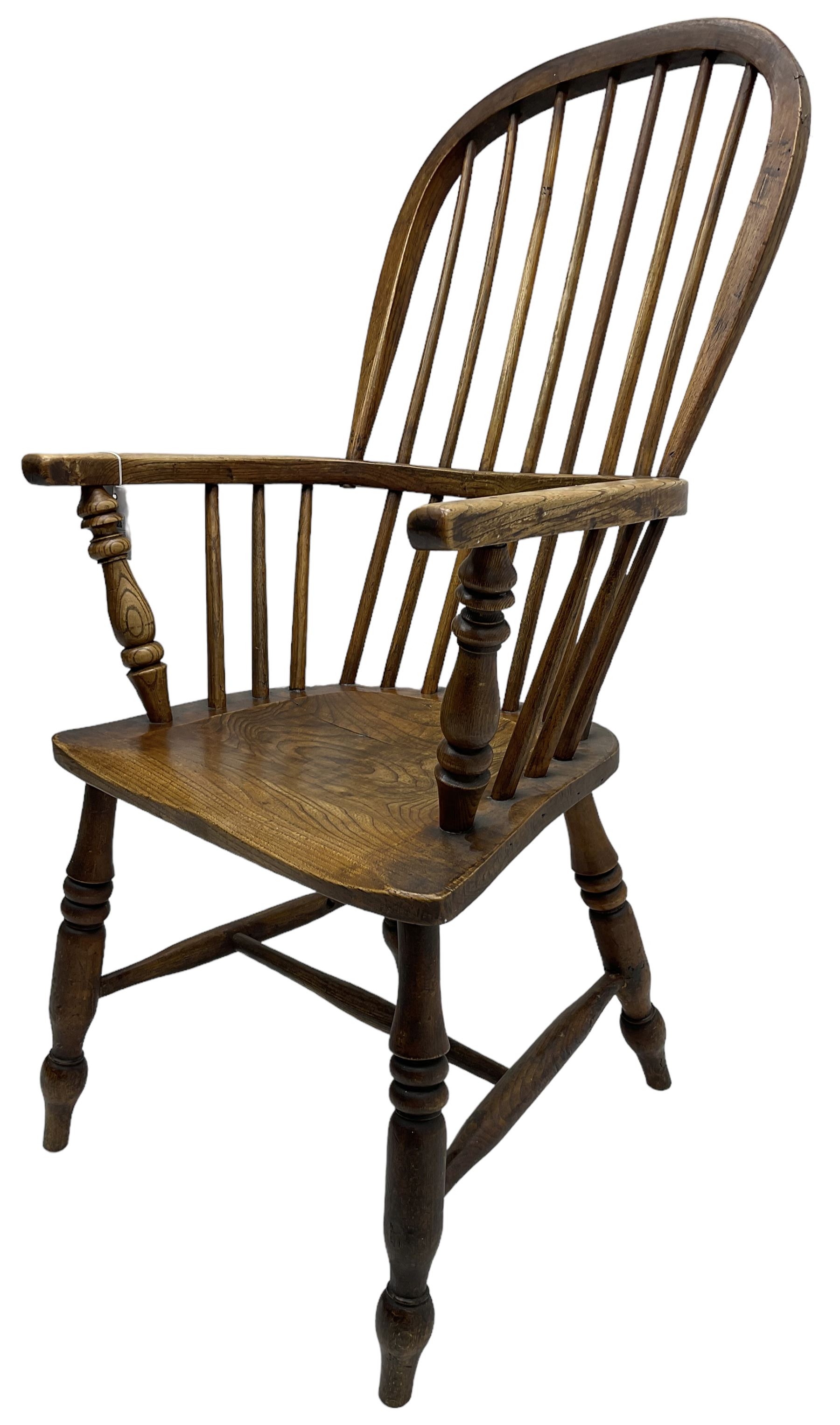 Early 19th century elm Windsor chair, high hoop and stick back over shaped saddle seat, raised on ring turned supports united by H-stretcher