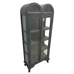 Tall painted glazed display cabinet, double arched top over two glazed doors, fitted with three shelves, in rustic blue paint finish, on cabriole feet