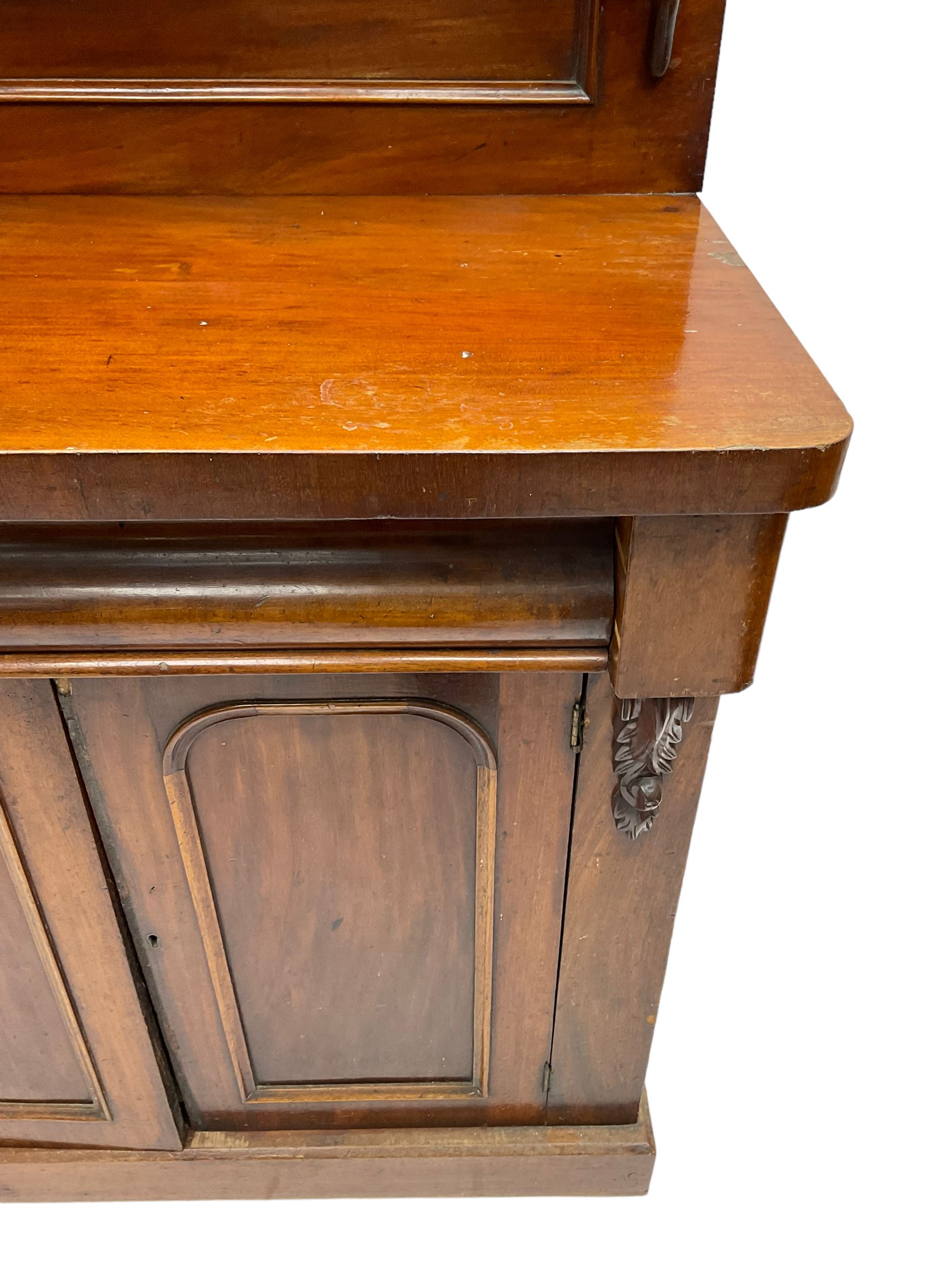 Victorian mahogany chiffonier, raised back with carved C-scroll foliage mounts and shelf, rectangular top with rounded corners over frieze drawer and double panelled cupboard, on skirted base