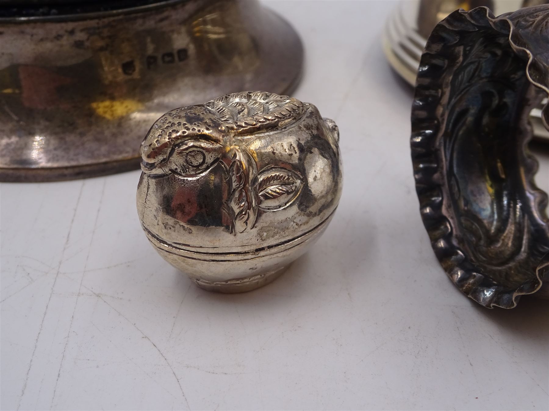 Group of silver, comprising silver mounted trinket box with pin cushion lid, bottle coaster with turned wooden centre, napkin ring, fish trinket box and a small 800 silver model of a boat, all stamped or hallmarked 