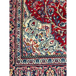 North west Persian Sarouk crimson ground rug, central floral medallion surrounded by scrolling branches decorated with foliage and stylised plant motifs, the main border decorated with repeating scrolling design with floral motifs, within guard stripes 