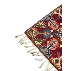 Caucasian design crewelwork hanging, crimson ground, the field decorated with geometric designs, the wide guard band with repeating stylised plant  motifs