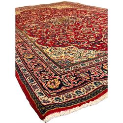 North west Persian Sarouk crimson ground rug, central floral medallion surrounded by scrolling branches decorated with foliage and stylised plant motifs, the main border decorated with repeating scrolling design with floral motifs, within guard stripes 