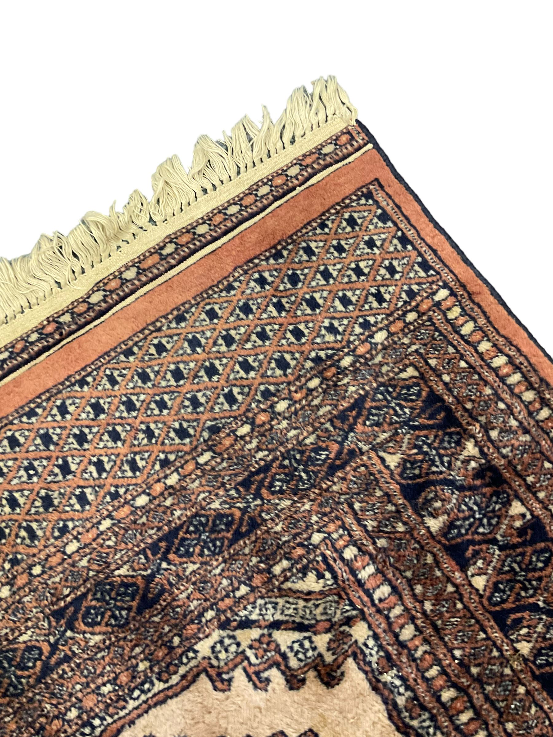 Persian peach ground rug, the field divided into four panels each with geometric lozenge, multiple band border with stylised flower head motifs, the end panels decorated with repeating lozenges