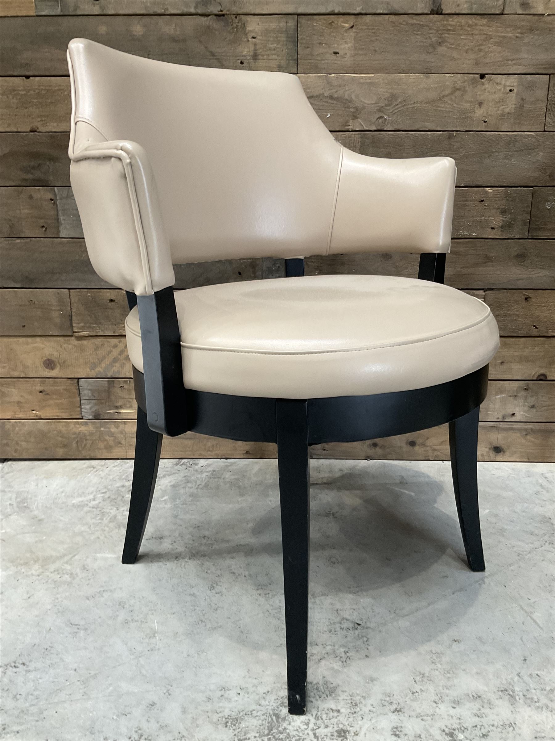 Four ebonised framed tub shaped armchairs, upholstered in beige fabric