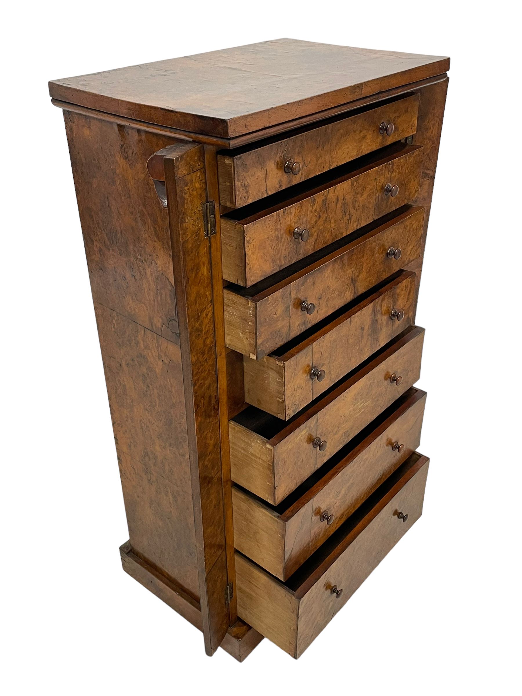 Victorian burr walnut Wellington chest, rectangular top with book-matched veneers, two hinged uprights with scrolled foliage carved brackets enclosing seven graduating drawers, on plinth base 