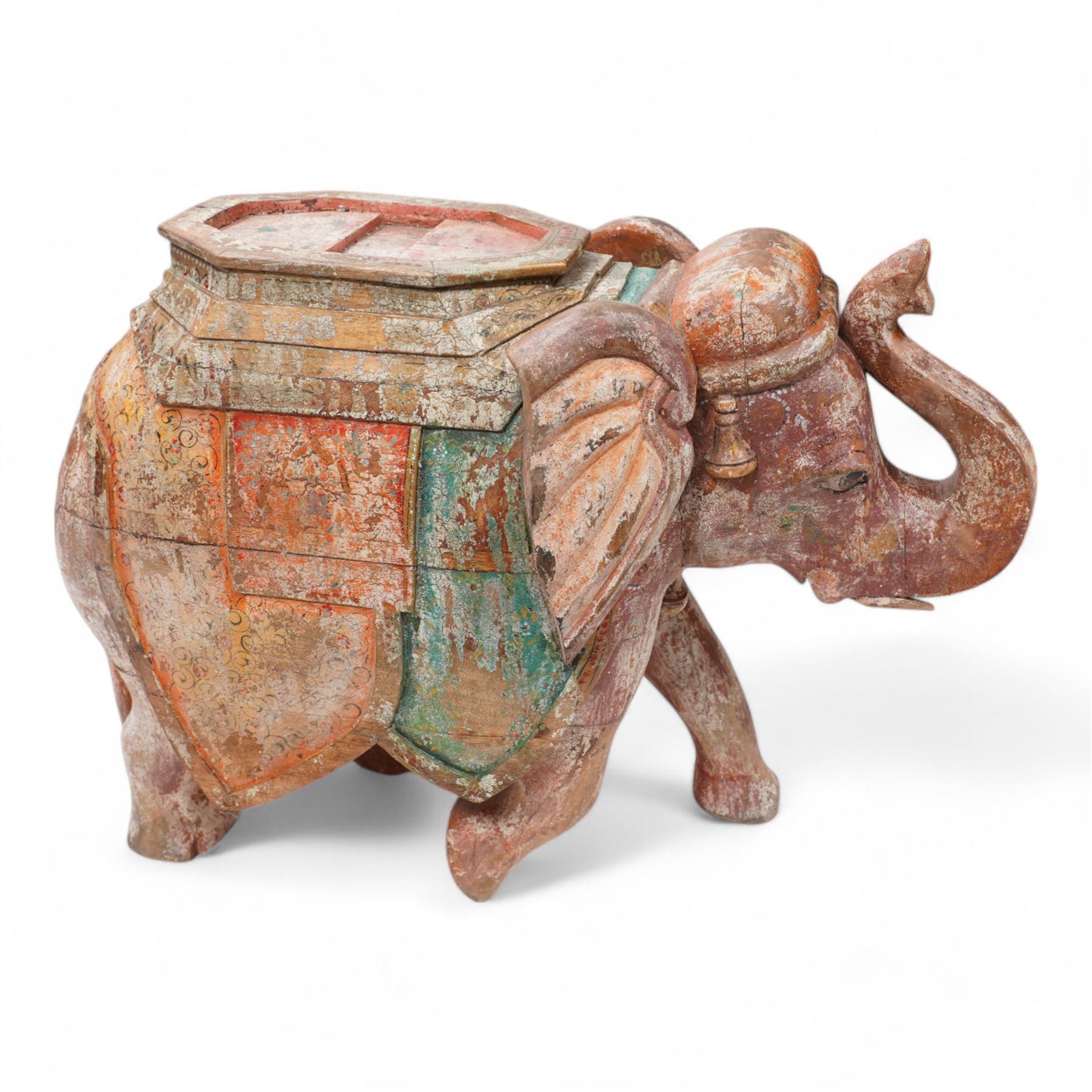 Early 20th century Indian hardwood and polychrome Elephant jardiniere stand, decorated with a headdress and vibrant saddle cloths, surmounted by an octagonal shaped saddle, with overall craquelure finish