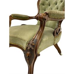 Pair of lady's and gentleman's Victorian carved walnut armchair and nursing chair, foliate carved cresting rail over shaped back with scrolled acanthus carved sides, the armchair with scroll arm terminals, the spoon back and sprung seat upholstered in buttoned sage green velvet, raised on cabriole supports with bell-flower moulded knees and scroll feet, on ceramic castors