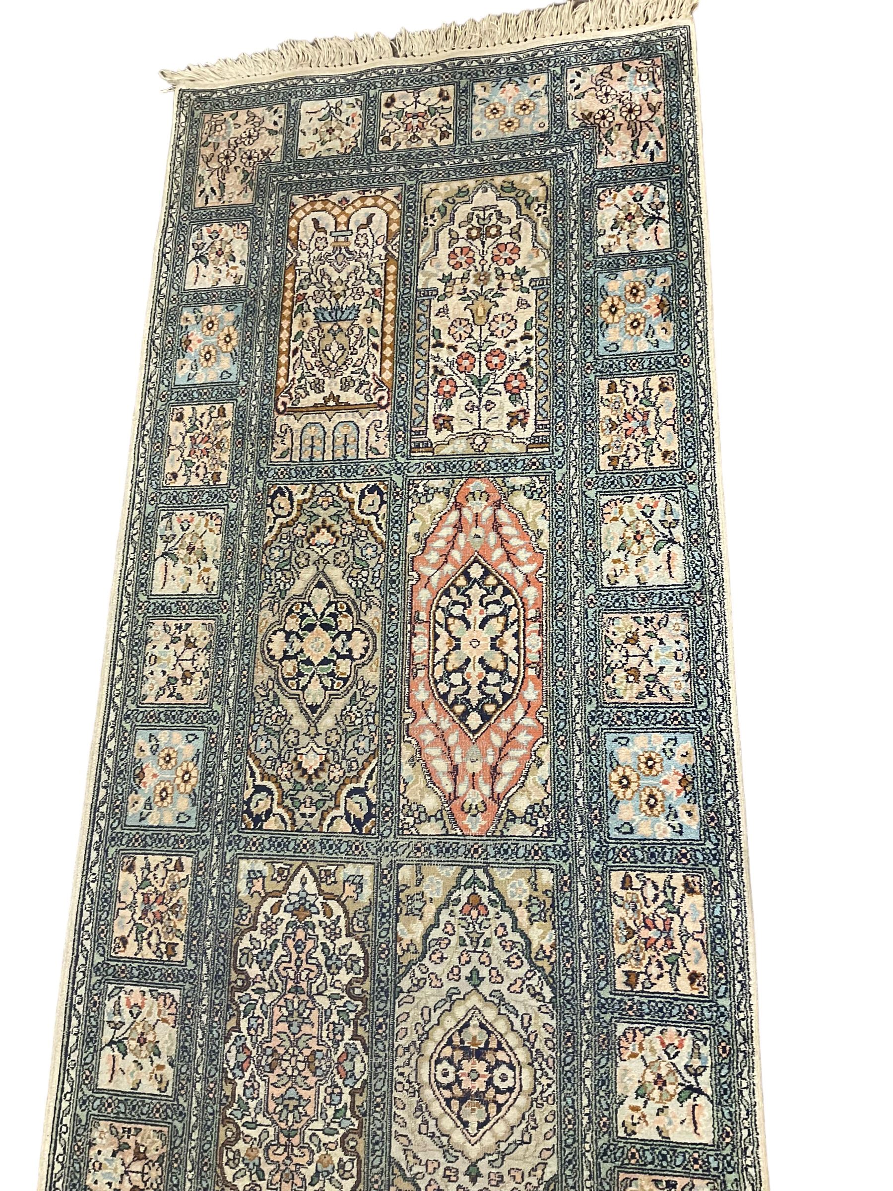 Fine Persian Kashmir ivory and pale indigo ground runner rug, the field decorated with sixteen rectangular panels depicting Mirab motifs and other traditional carpet designs, the border with repeating square panels of floral bouquets and foliate patterns