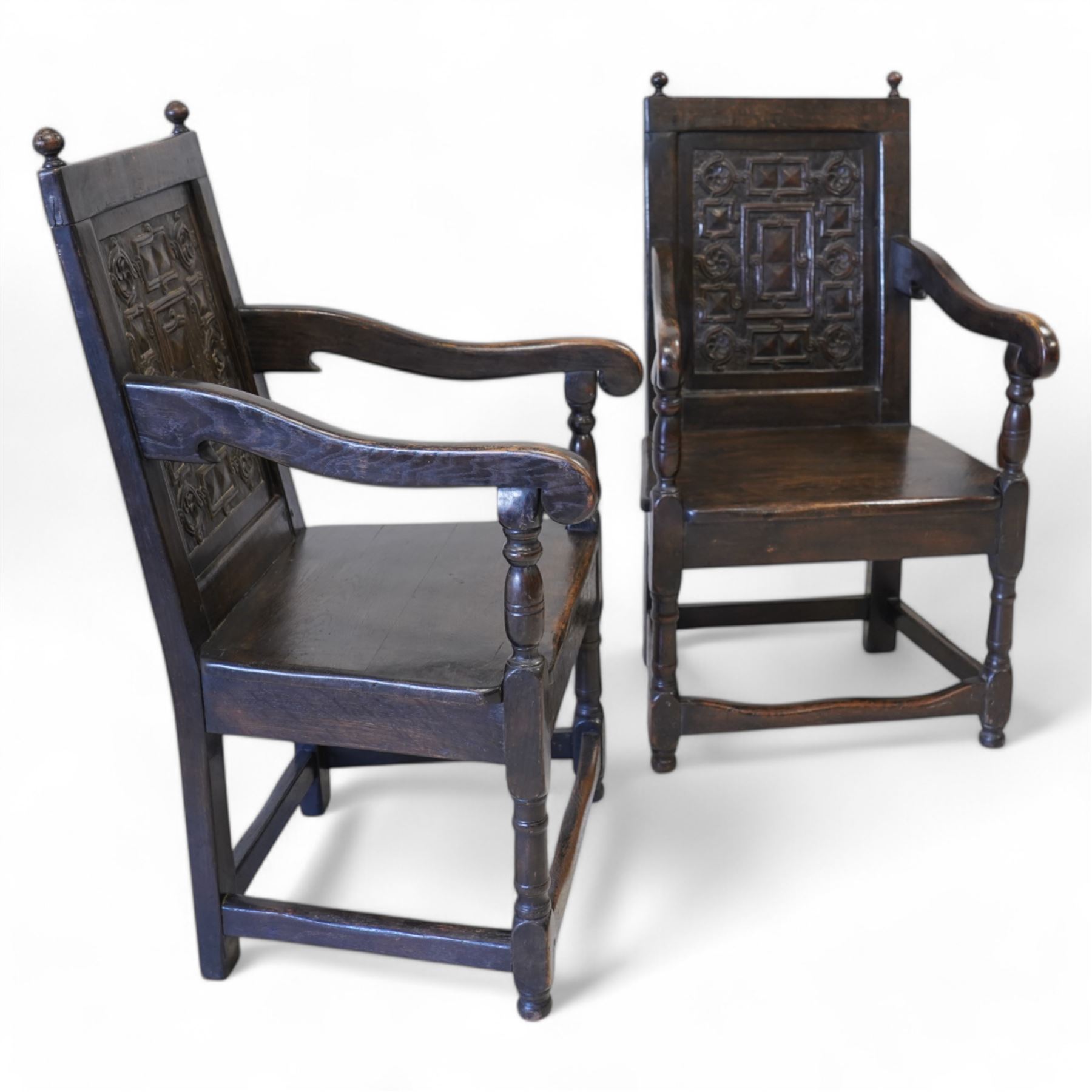 Pair 17th century design wainscot open armchairs, the cresting rail with turned finals over panelled back, the panel carved with geometric pattern and flower heads, shaped arms over plank seat, on turned supports united by stretchers 