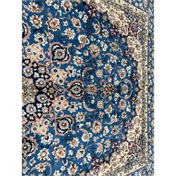 Persian Nain blue ground carpet, overall arabesque design, centre rosette medallion with eight projecting palmettes, the surrounding field decorated with interlacing branches and stylised plant motifs, within floral pale ground spandrels, the guarded border decorated with repeating stylised floral pattern 