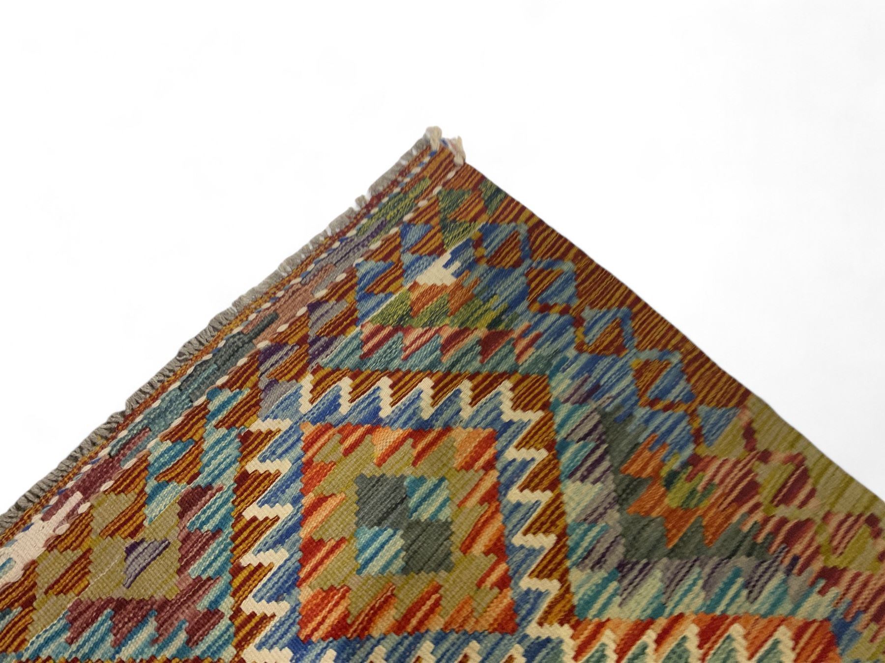 Chobi kilim multi-coloured rug, the field decorated with various lozenges of contrasting colours with ivory outlines, enclosed by a guard band with repeating geometric patterns