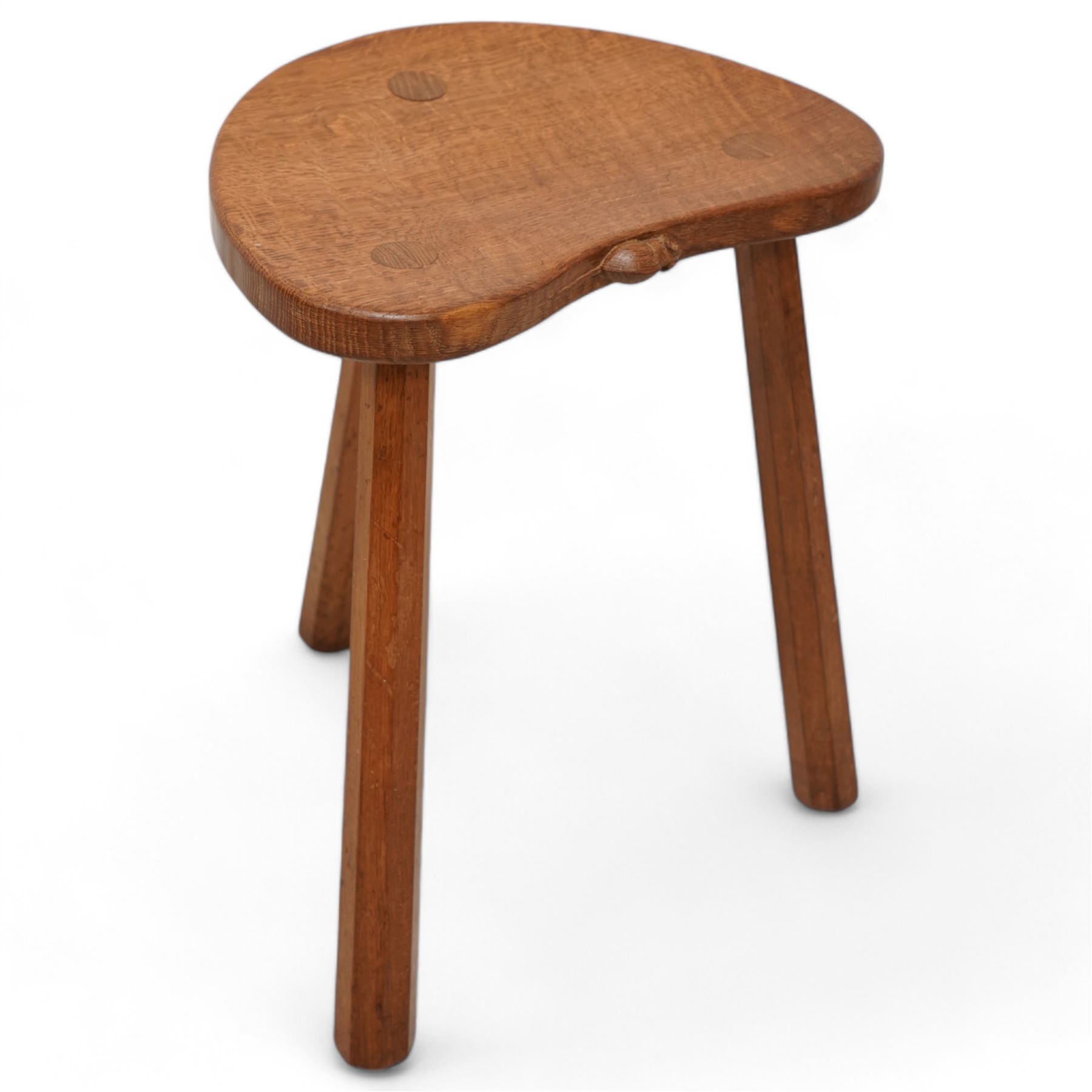 Mouseman - oak three-legged stool, dished kidney-shaped seat on three octagonal splayed supports, carved with mouse signature, by the workshop of Robert Thompson, Kilburn