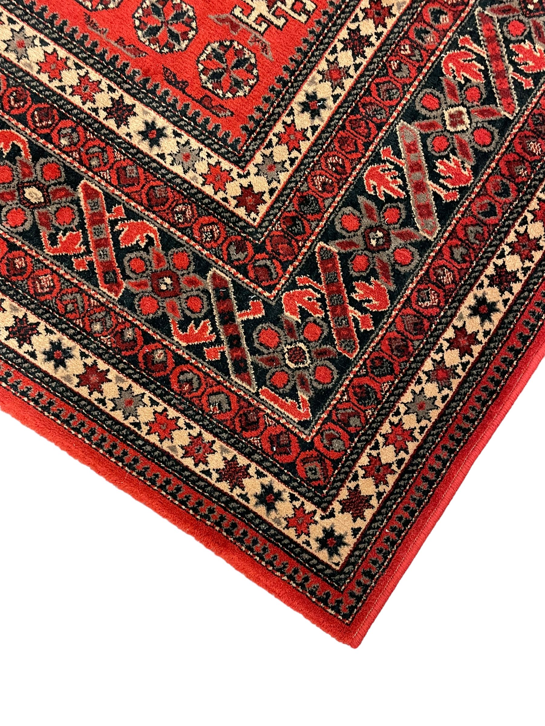 Persian design red ground rug, the field decorated with geometric motifs, repeating multiple band border 