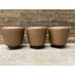 Three circular tapered stools, upholstered in copper fabric