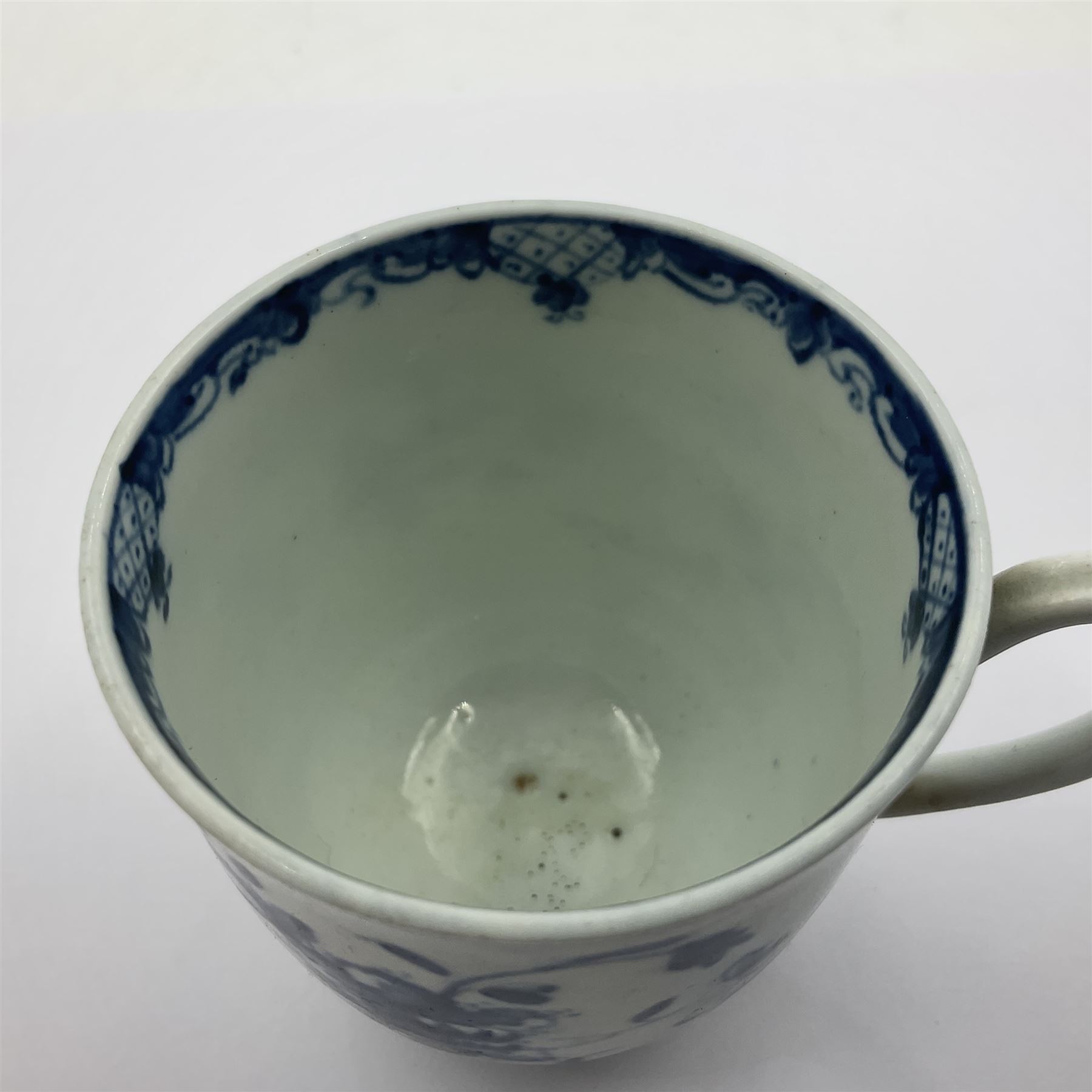 Two 18th century Worcester porcelain coffee cups, the first example decorated in the Plantation pattern, circa 1754, the second decorated in the Mansfield pattern, circa 1760, with workman's mark beneath, each approximately H5.5cm