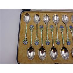 Set of twelve silver coffee spoons, each with enamelled blue flower to terminal and green and white enamel decoration to stem, hallmarked Mappin & Webb Ltd, Birmingham 1934, contained within fitted case