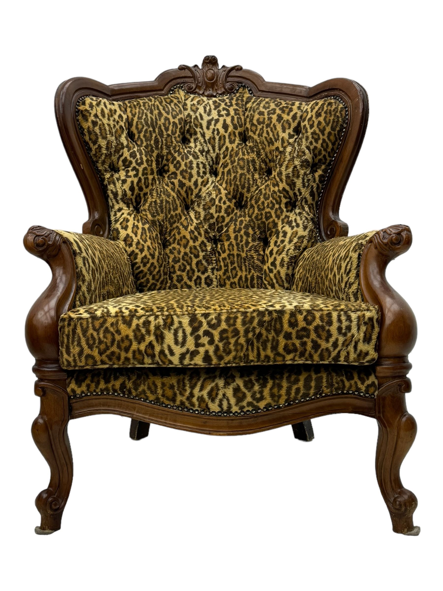 Pair of Victorian design stained beech armchairs, upholstered in leopard print fabric, with carved top rail over button-tufted backrest, scroll arms, serpentine front rail, raised on cariole supports