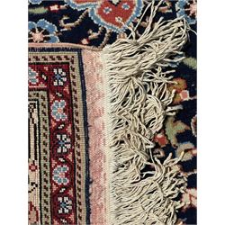 Indo-Persian indigo ground rug, the floral design peach medallion surrounded by trailing and interlaced branches and flower heads, the main border decorated with repeating stylised plant motifs within floral guard stripes 