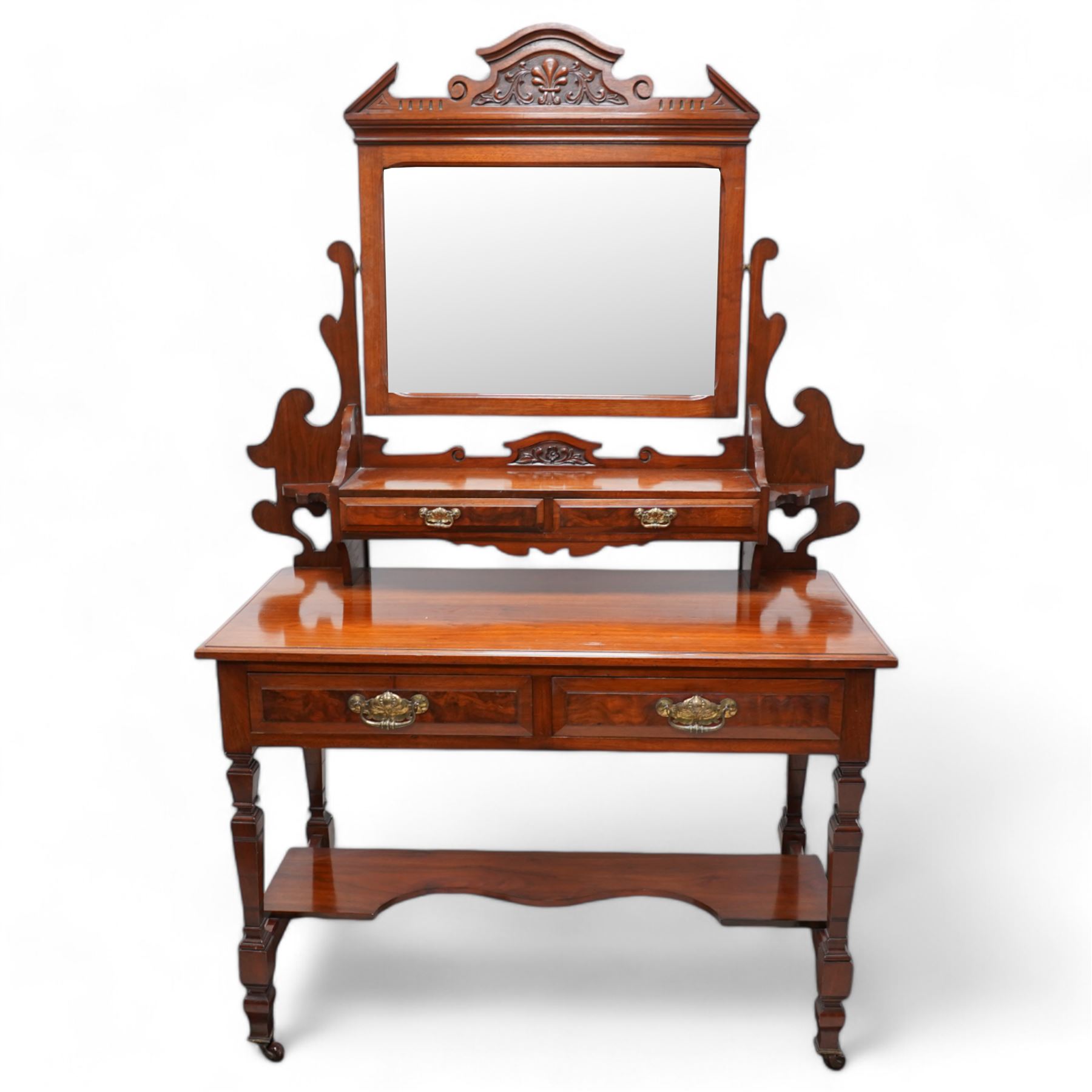 Late Victorian walnut dressing table, raised swing mirror back over two trinket drawers with brass Art Nouveau handle plates, rectangular top fitted with two further drawers, raised on square ring-turned supports united by shaped under-tier, on castors