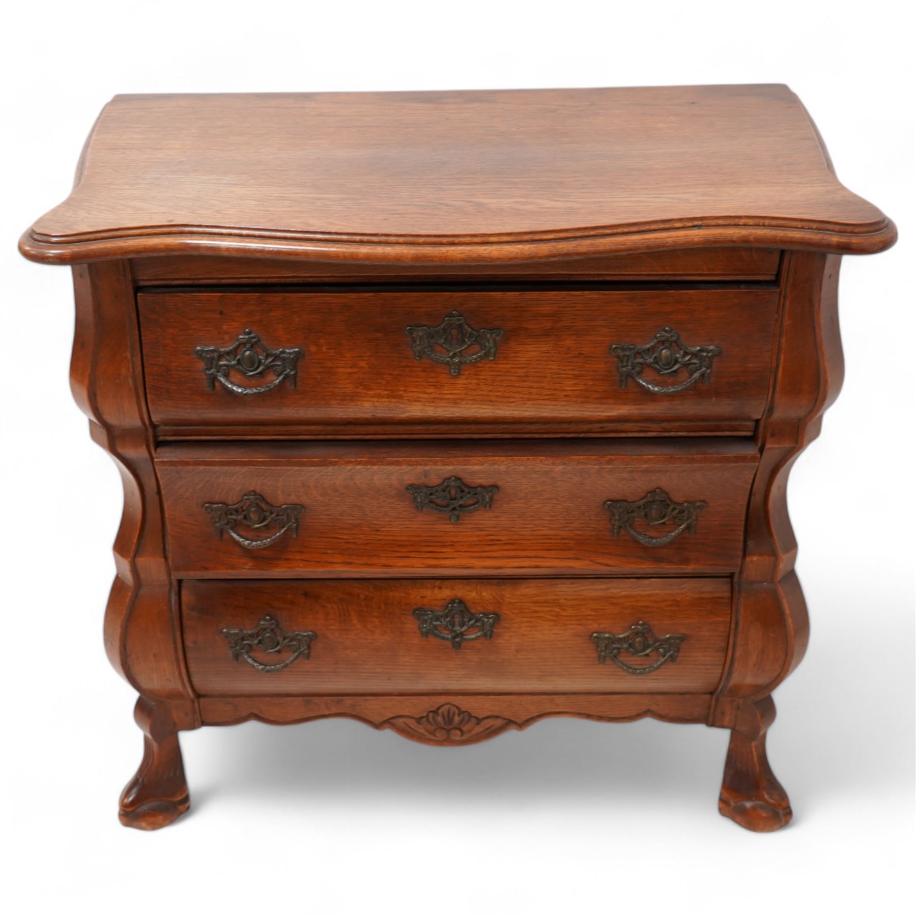 Early 20th century Dutch oak bombe chest, shaped rectangular top with moulded edge, fitted with three drawers flanked by moulded uprights, on hairy ball-and-claw feet