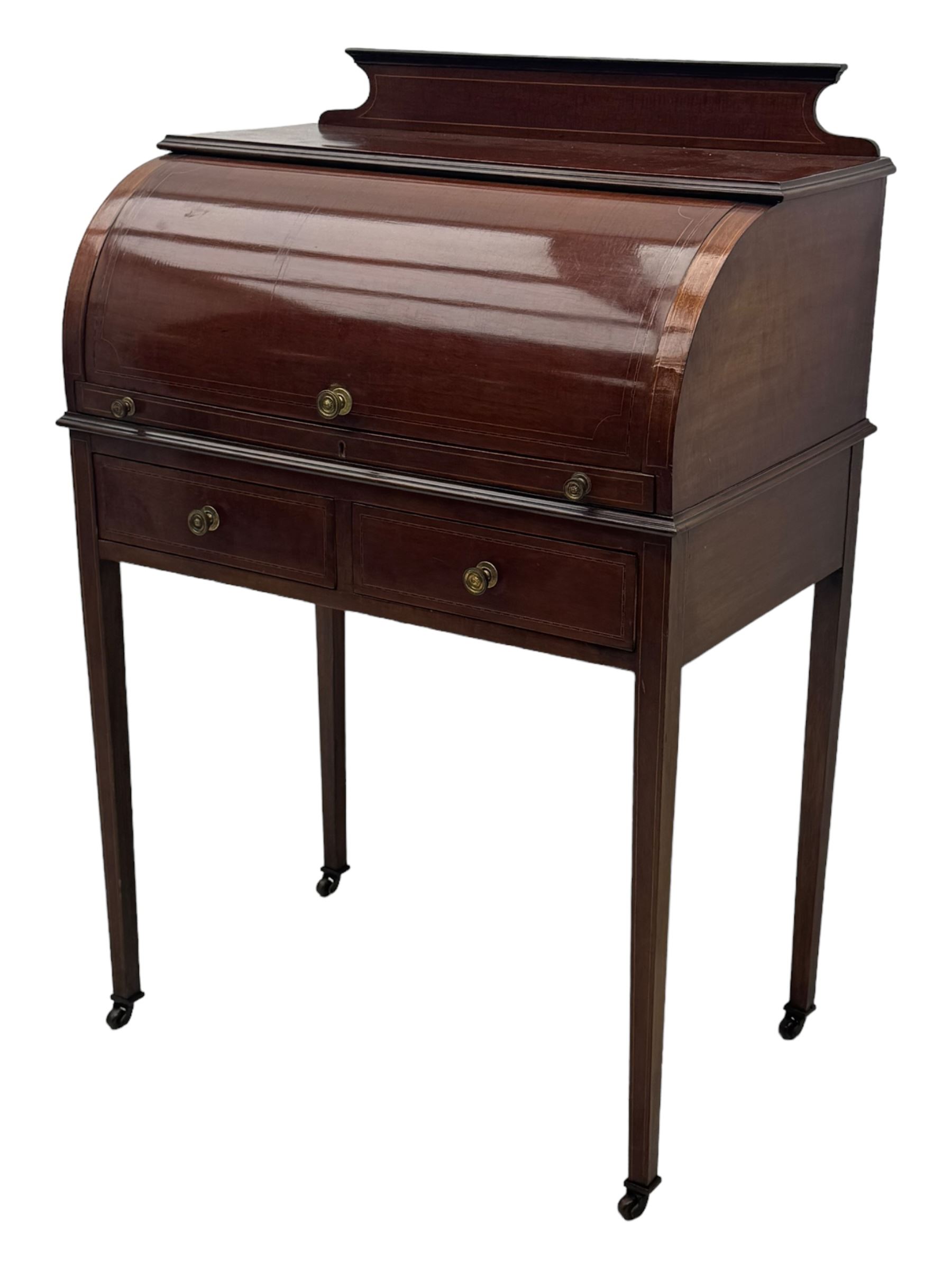 Edwardian inlaid mahogany roll-top desk, cylindrical lid enclosing fitted interior with pigeonholes, drawers and retractable writing surface, over two drawers with brass pull handles, on tapered supports with brass and ceramic castors