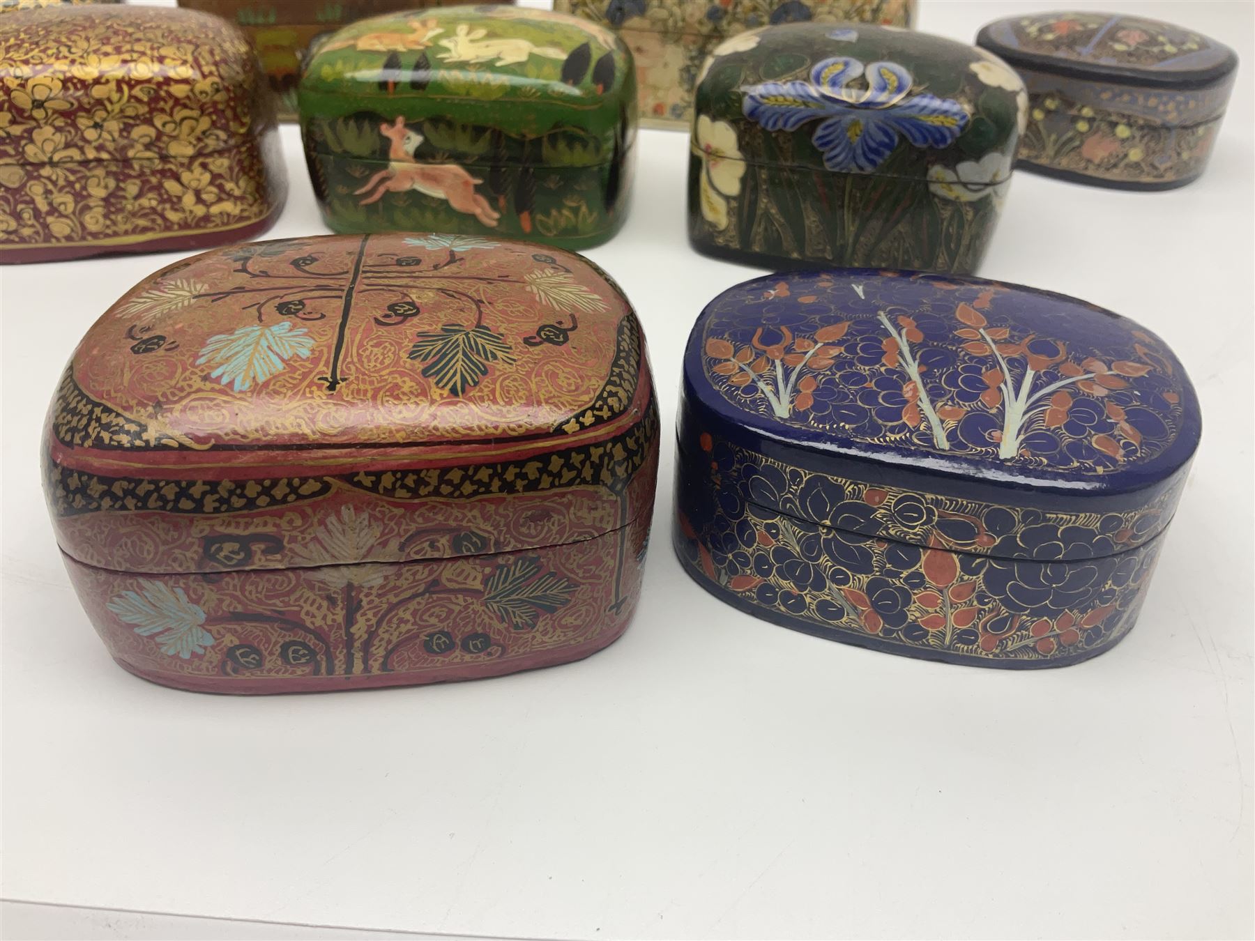 Nine lacquered boxes, all rectangular form, including russian examples decorated with animals within a stylized landscapes and example with flower decoration, largest H7cm, L11cm