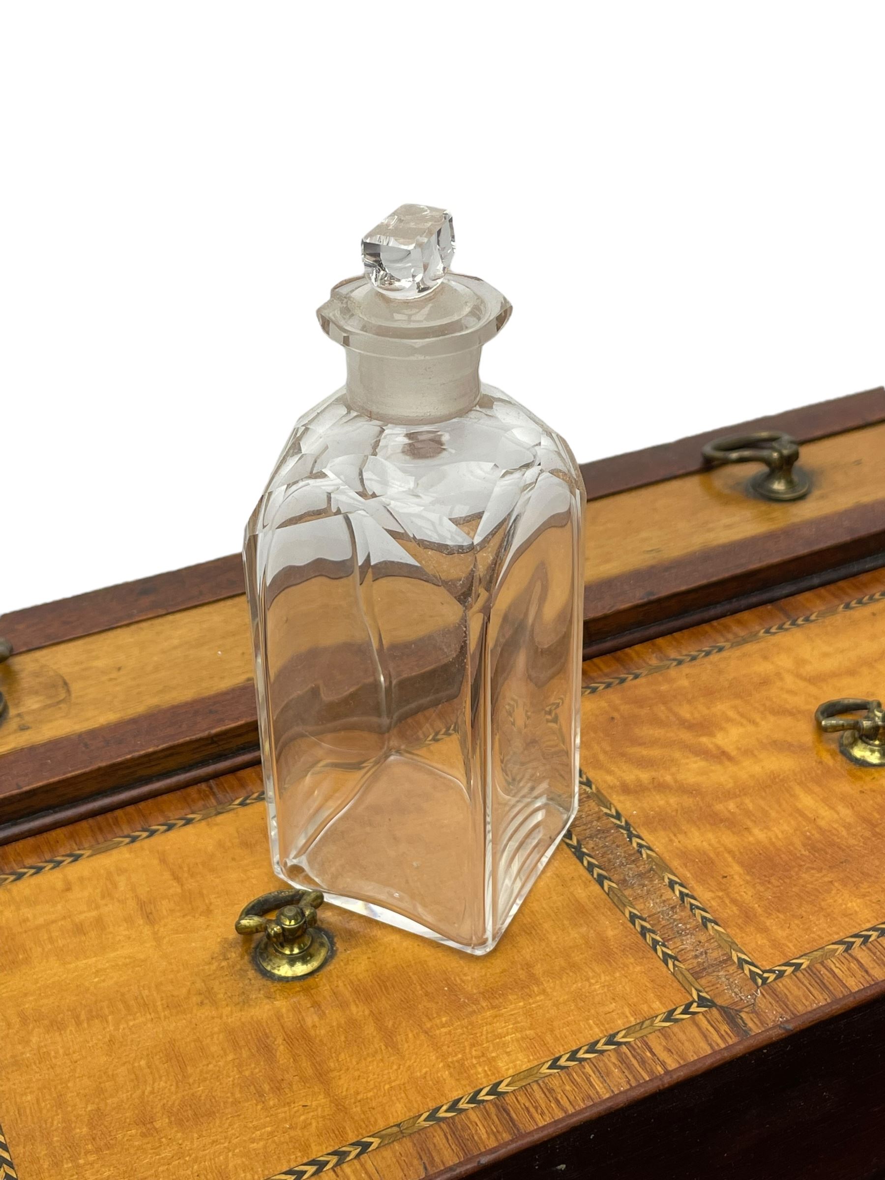 Late 19th century mahogany and satinwood dressing chest, the raised middle section hinges to reveal an interior fitted with lidded compartments, removable tray, single drawer and glass scent bottles, lift-up bevelled mirror with adjustable hinged mechanism, fitted with a further eight cock-beaded graduating drawers and curved kneehole with double cupboard, square tapering supports on brass cups and castors, inlaid throughout with checkered stringing, ornate Rococo cast gilt metal handles