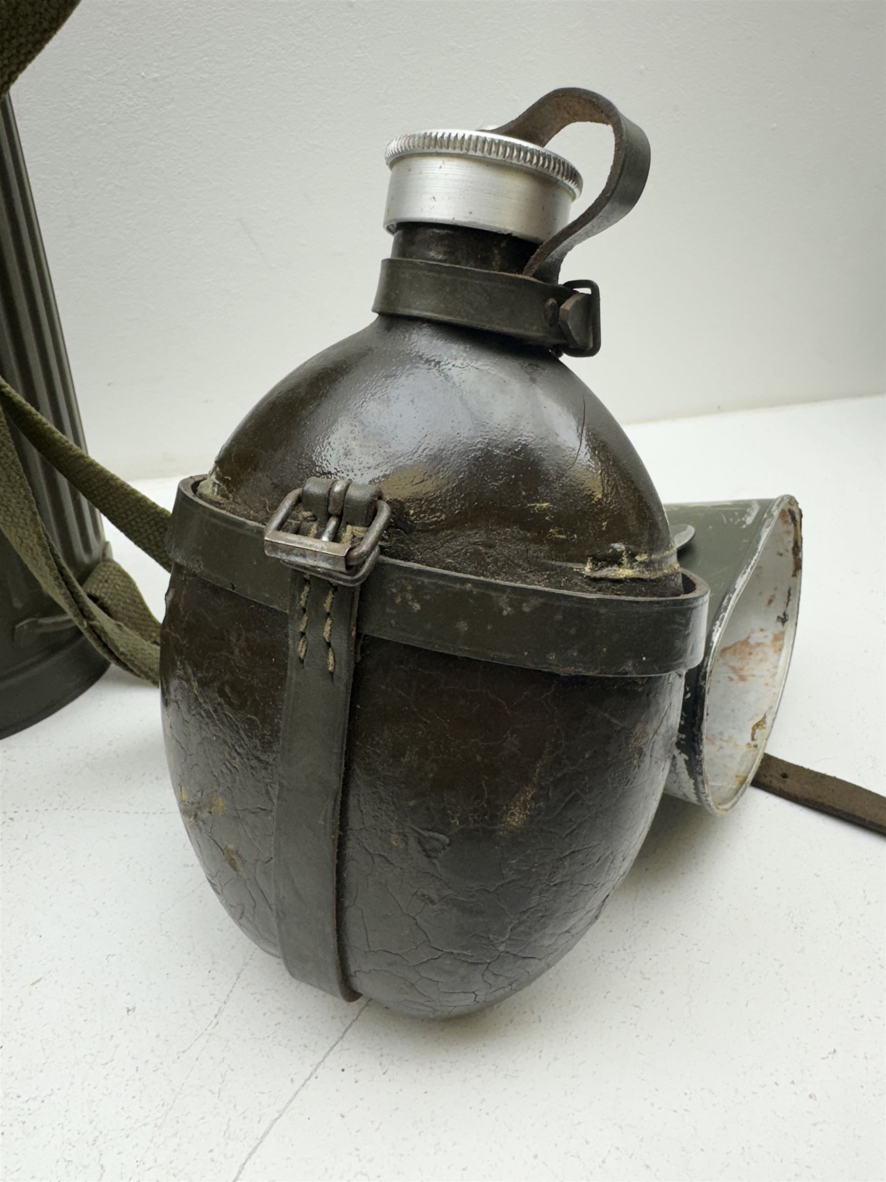 Two WWII German army canteen water bottles, together with German gas mask marked FE55 in a green fluted tin canister