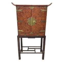 Chinese design bamboo and wood altar cabinet on stand, parquetry lattice-work bamboo, two doors with engraved metal fixtures enclosing drawers and shelf, fitted with slide, the stand pm square supports joined by a series of geometric stretchers