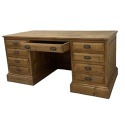 20th century waxed pine kneehole desk, rectangular top over nine drawers with cup handles, on moulded plinth base