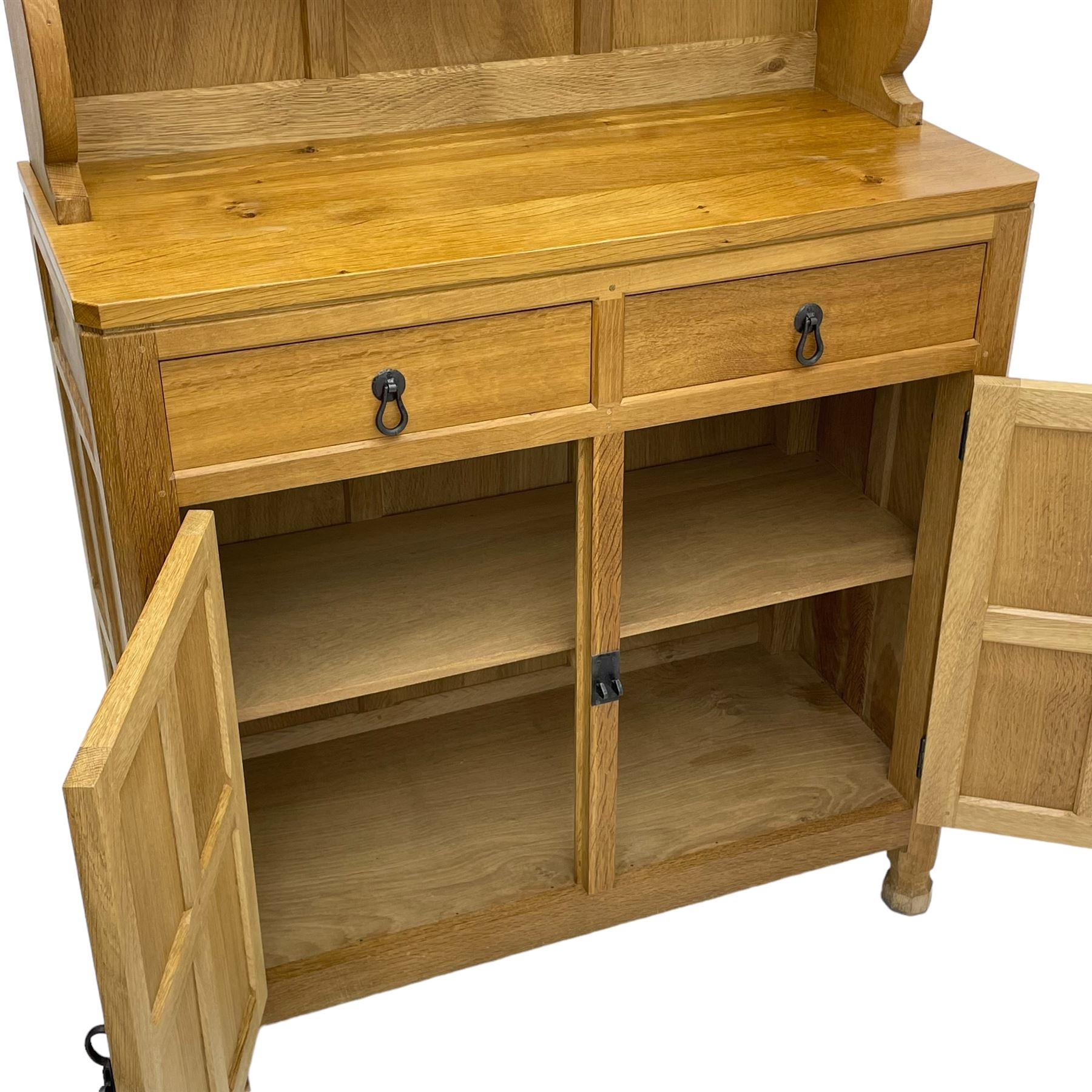 Mouseman - oak dresser, penny moulded cresting rail over two shelves supported by shaped ends, canted rectangular adzed top, fitted with two drawers and panelled cupboards, with wrought iron hinges and catches, on octagonal feet, carved with mouse signature, by the workshop of Robert Thompson, Kilburn 