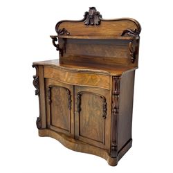 Mid-19th century rosewood chiffonier, raised back with scroll and leaf carved shaped pediment, serpentine top over drawer and double cupboard with scrollwork decoration, on shaped plinth base