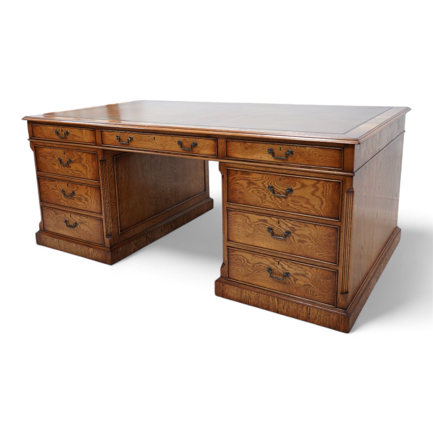 Georgian design figured oak twin pedestal desk, moulded rectangular top with brown leather inset, fitted with nine graduating cock-beaded drawers, canted corners with fluted decoration, on moulded plinth base 