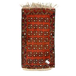 Small Persian red ground rug, the field decorated with four rows of Gul motifs
