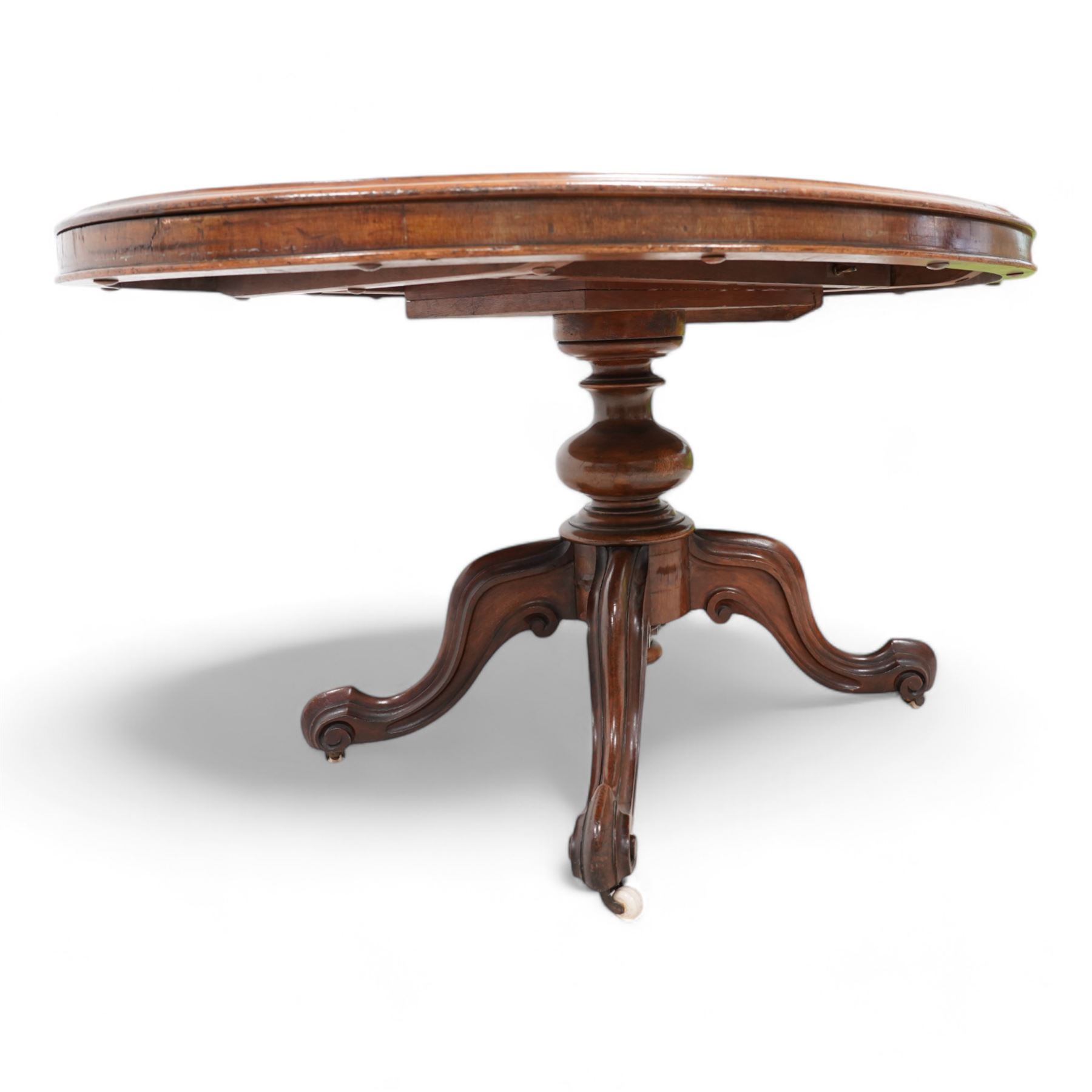 Victorian mahogany loo or centre table, moulded oval tilt-top, turned pedestal on four out splayed carved supports with scrolled terminals, on brass and ceramic castors 