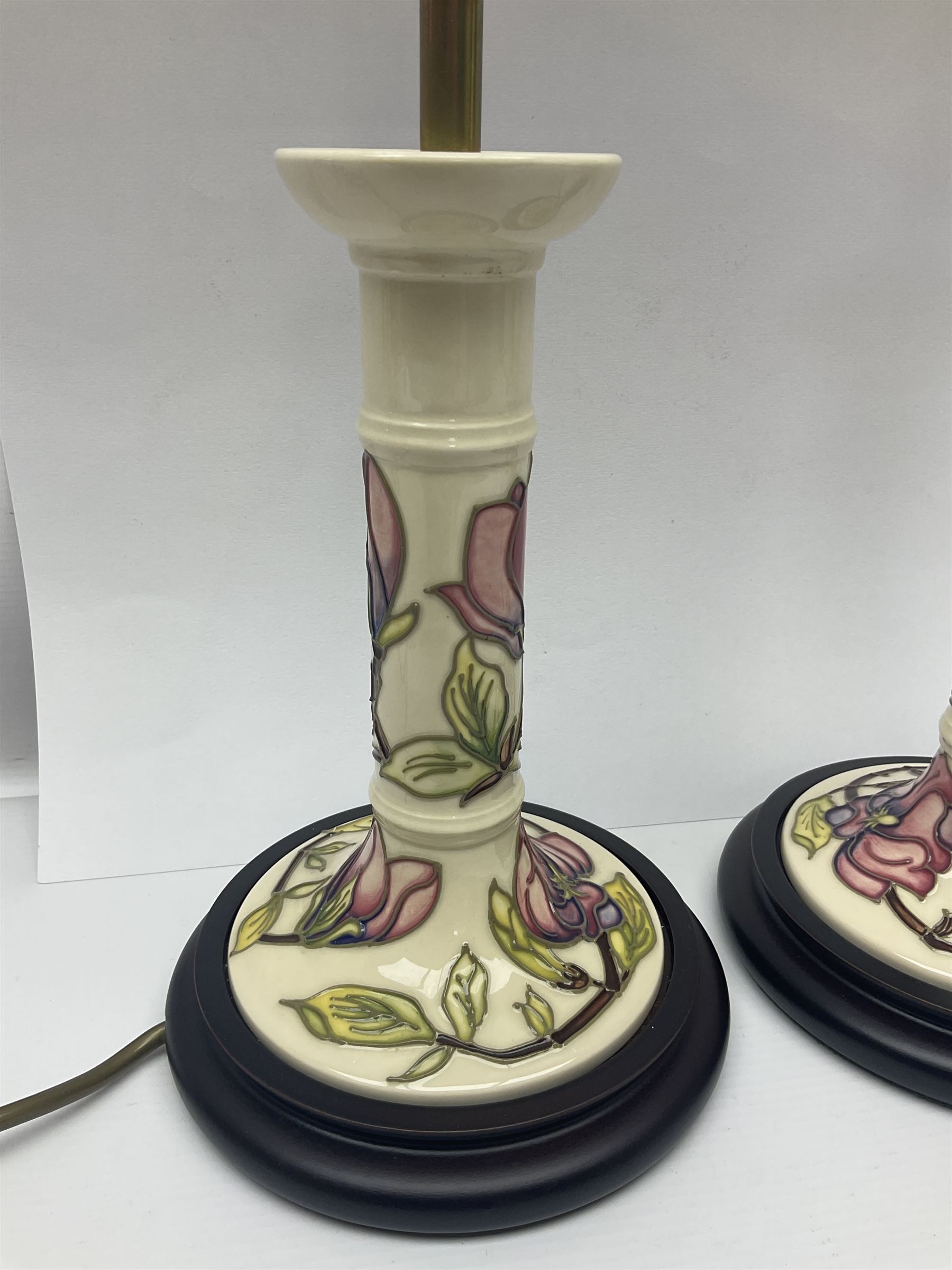 Pair of Moorcroft table lamps of candlestick form in magnolia pattern, with Moorcroft shades, H50cm 
