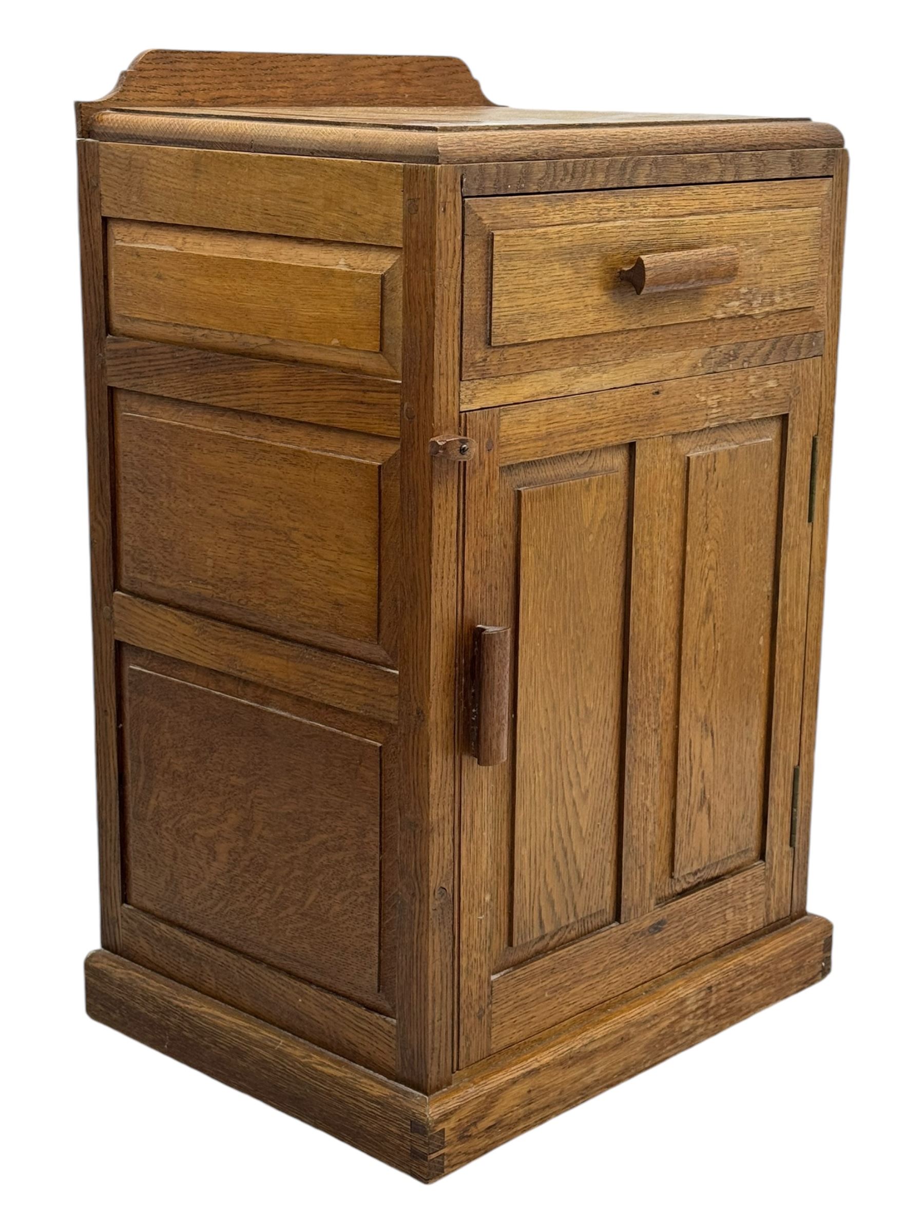 Arts & Crafts period oak bedside cupboard, raised back over moulded top, fitted with single drawer over panelled cupboard, panelled sides, on chamfered plinth base 